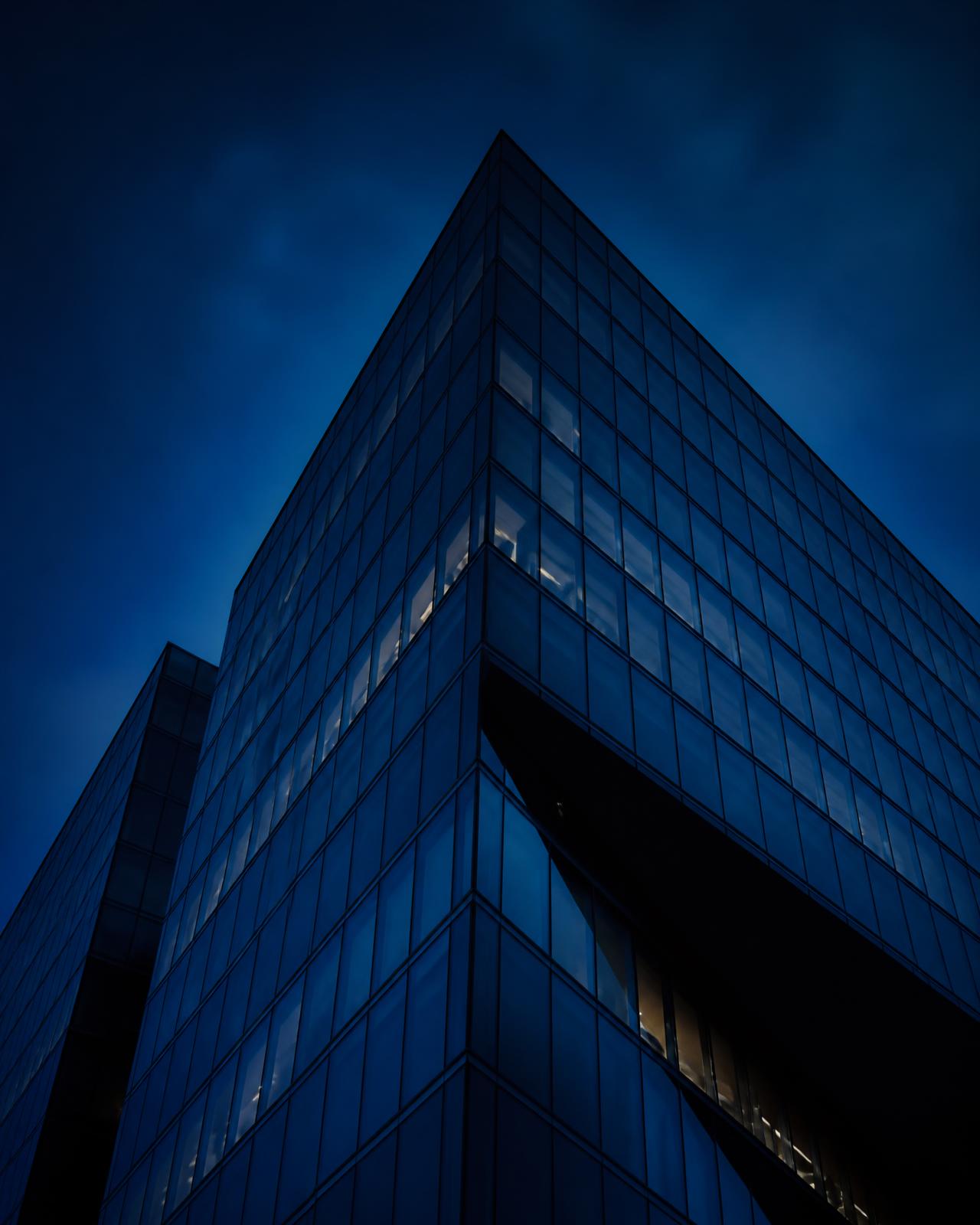 Glass corporate tower at dusk in deep navy tones